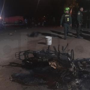 En primer plano la motocicleta incinerada por la turba y al fondo el cuerpo del presunto Pistolero que acabó con la vida de la mujer y luego linchado por la comunidad.