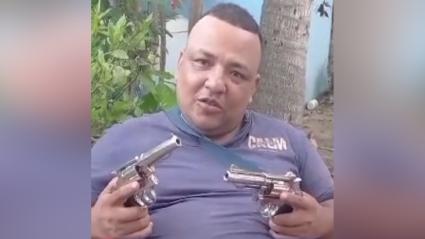 Uno de los extorsionistas muestra armas de fuego a lo largo de su amenaza